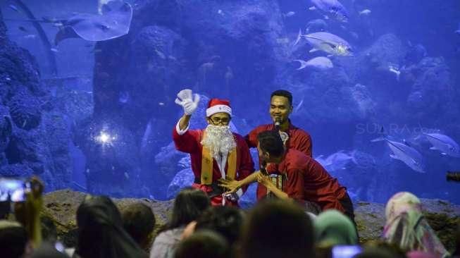 Pengunjung menyaksikan atraksi para Santa Claus saat memberikan makan kepada ribuan biota laut di wahana Sea World Taman Impian Jaya Ancol, Jakarta, Minggu (25/12/2016). [Suara.com/Kurniawan Mas'ud]