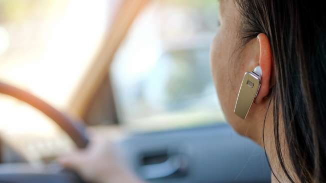 Ilustrasi berkendara menggunakan hands-free untuk menerima panggilan telepon. [Shutterstock]