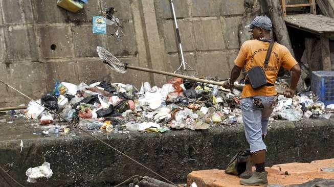 Petugas UPK Badan Air Taman Jalur Hijau Provinsi DKI Jakarta membersihkan sampah yang terbawa oleh aliran Kali Kwitang, di Jakarta, Kamis (12/1).