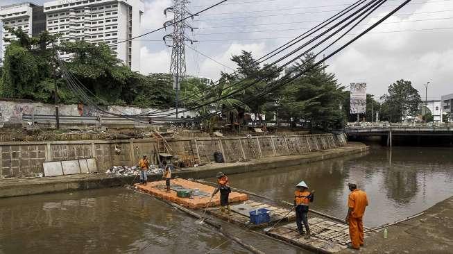 Petugas UPK Badan Air Taman Jalur Hijau Provinsi DKI Jakarta membersihkan sampah yang terbawa oleh aliran Kali Kwitang, di Jakarta, Kamis (12/1).