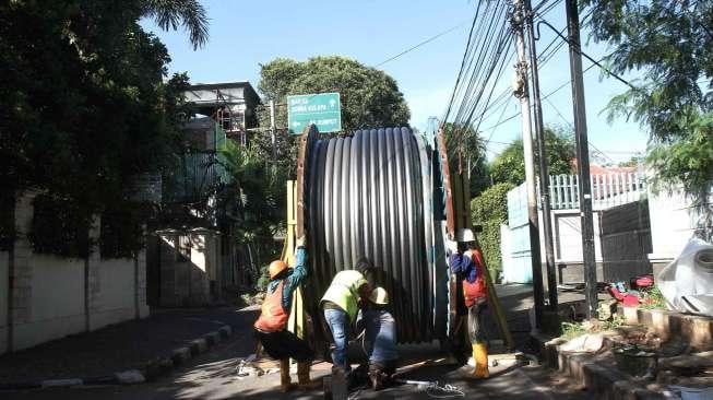 Pekerja menurunkan kabel bertegangan tinggi untuk dipasang di bawah tanah di kawasan Jalan Proklamasi, Jakarta, Jumat (19/1).