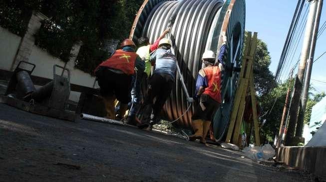 Pekerja menurunkan kabel bertegangan tinggi untuk dipasang di bawah tanah di kawasan Jalan Proklamasi, Jakarta, Jumat (19/1).