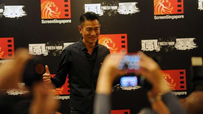 Aktor Andy Lau berpose setelah konferensi pers di Singapura, 4 Desember 2013 [AFP]