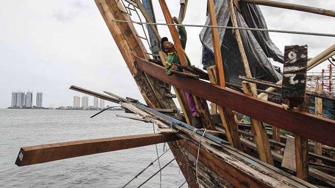 Pekerja tampak memperbaiki kapal pengangkap ikan yang berlabuh di dermaga Pelabuhan Ikan Muara Angke, Jakarta, Sabtu (28/1/2017). [Suara.com/Kurniawan Mas'ud]