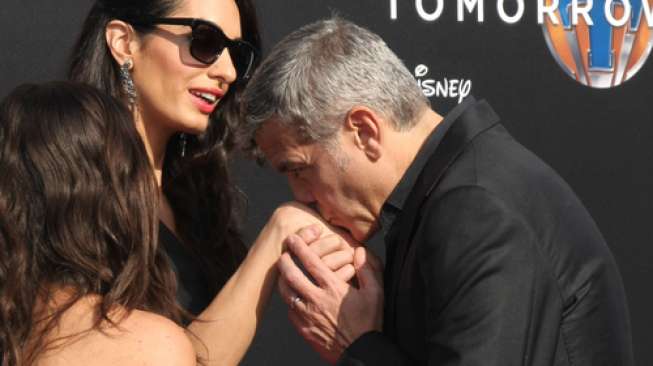 George Clooney mencium tangan istrinya, Amal Alamuddin Clooney di premiere film Tomorrowland di AMC Downtown Disney, Lake Buena Vista, California, pada 9 Mei 2015. [shutterstock]