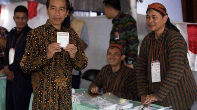 Presiden Joko Widodo didampingi istri, Iriana Widodo menggunakan hak suara dalam Pilkada DKI Jakarta di TPS 04 Gambir, Jakarta, Rabu (15/2). 