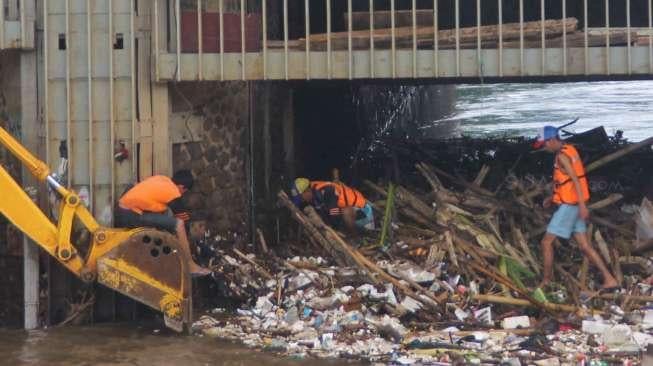 Petugas membersihkan sampah pada aliran Sungai Ciliwung yang menyumbat di Pintu Air Manggarai, Jakarta, Sabtu (18/2).