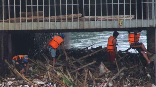 Petugas membersihkan sampah pada aliran Sungai Ciliwung yang menyumbat di Pintu Air Manggarai, Jakarta, Sabtu (18/2).