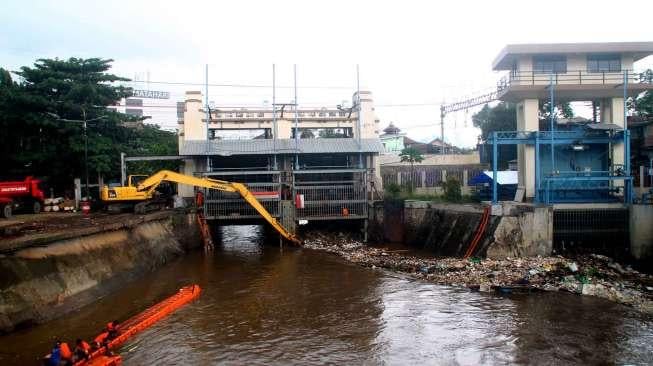 Petugas membersihkan sampah pada aliran Sungai Ciliwung yang menyumbat di Pintu Air Manggarai, Jakarta, Sabtu (18/2).