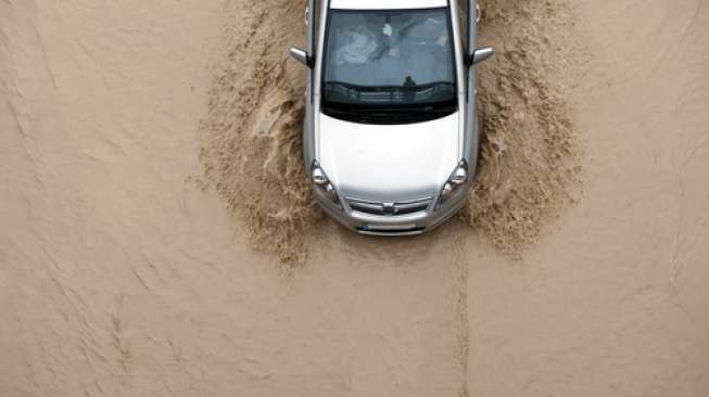 Ilustrasi sebuah mobil melewati luapan banjir (Shutterstock).