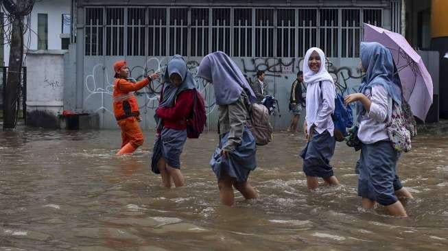 Warga melintasi banjir di kawasan Bendungan Hilir, Jakarta, Selasa (21/2).