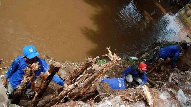 Pekerja Harian Lepas (PHL) Dinas Tata Air DKI Jakarta membetulkan turap air yang longsor di kawasan Matraman, Jakarta, Minggu (26/2/2017). [Suara.com/Oke Atmaja]