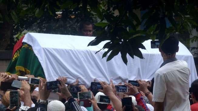 Prajurit TNI dan khalayak menggotong peti jenazah KH Hasyim Muzadi saat akan dimakamkan di Kompleks Pondok Pesantren Al Hikam, Beji, Depok, Jawa Barat, Kamis (16/3/2017). [Suara.com/Oke Atmaja]