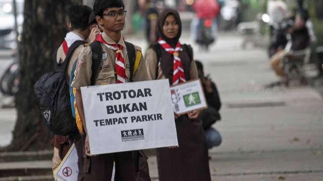 Aktivis Koalisi Pejalan Kaki dan Pramuka melakukan aksi peduli pejalan kaki di kawasan pedestrian Jalan Merdeka Selatan, Jakarta, Jumat (17/3).