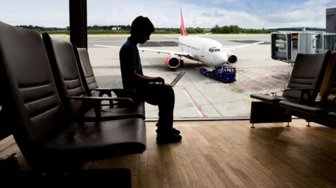 Ilustrasi seseorang sedang menggunakan laptop di bandara (Shutterstock).