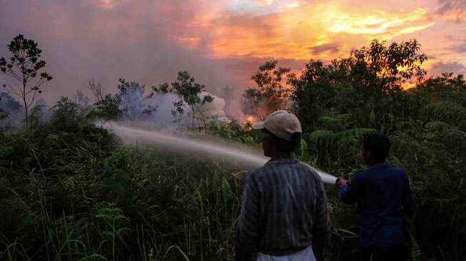 Petugas pemadam kebakaran dibantu Masyarakat Peduli Api (MPA) berusaha memadamkan api saat kebakaran lahan gambut di Pekanbaru, Riau, Senin (3/4).