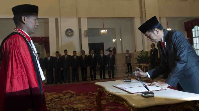 Presiden Joko Widodo (kanan) mendatangani dokumen pelantikan Saldi Isra (kiri) sebagai Hakim Mahkamah Konstitusi pada acara pelantikan di Istana Negara, Jakarta, Selasa (11/4). 