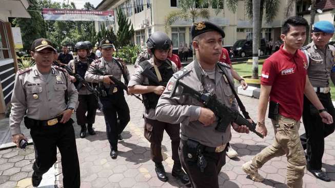 Dengan cara menabrakkan sepeda motor dan membacok dua anggota polisi. 