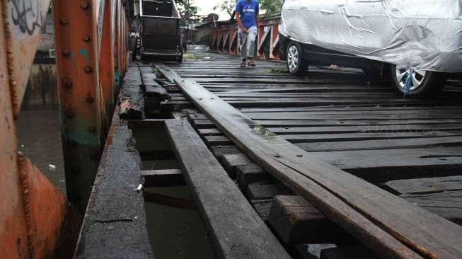 Warga melintasi jembatan yang rusak di Karet, Jakarta, Selasa (18/4).