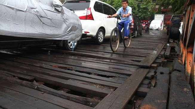 Warga melintasi jembatan yang rusak di Karet, Jakarta, Selasa (18/4).