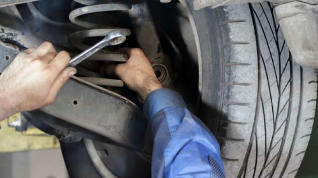 Ilustrasi tenaga mekanik tengah memperbaiki suspensi mobil. (Shutterstock)