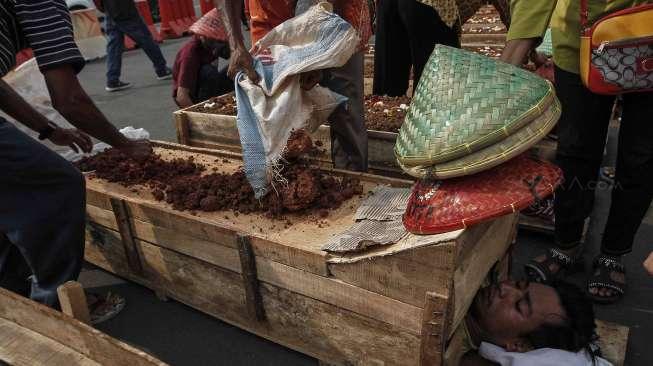 Puluhan anak usia 10-14 tahun warga Teluk Jambe melakukan aksi kubur diri di depan Istana Merdeka, Jakarta, Selasa (2/5).