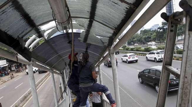 Petugas melakukan perbaikan atap kanopi halte  Transjakarta di Pancoran Barat, Jakarta, Kamis (11/5).