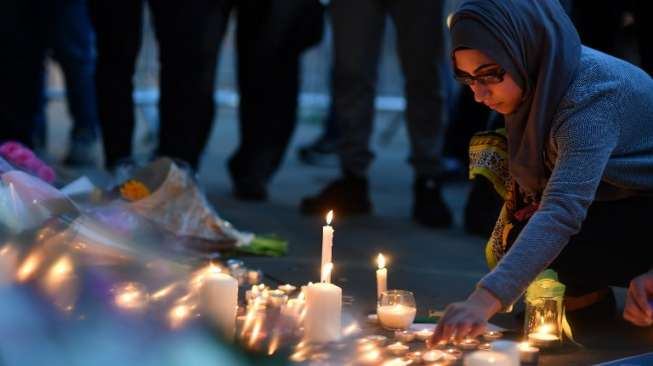 Masyarakat menyalakan lilin dan berdoa di kawasan Albert Square, Manchester, sebagai aksi solidaritas bagi korban aksi bom bunuh diri di Manchester Arena, Senin (22/5/2017) malam. (AFP)