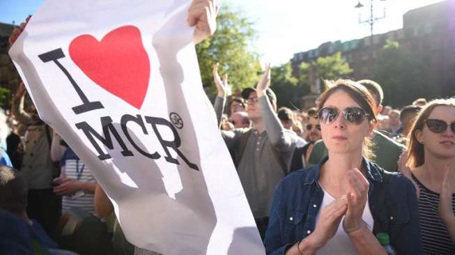 Masyarakat menyalakan lilin dan berdoa di kawasan Albert Square, Manchester, sebagai aksi solidaritas bagi korban aksi bom bunuh diri di Manchester Arena, Senin (22/5/2017) malam. (AFP)