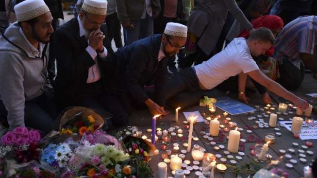 Masyarakat menyalakan lilin dan berdoa di kawasan Albert Square, Manchester, sebagai aksi solidaritas bagi korban aksi bom bunuh diri di Manchester Arena, Senin (22/5/2017) malam. (AFP)