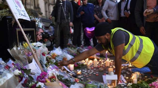 Masyarakat menyalakan lilin dan berdoa di kawasan Albert Square, Manchester, sebagai aksi solidaritas bagi korban aksi bom bunuh diri di Manchester Arena, Senin (22/5/2017) malam. (AFP)