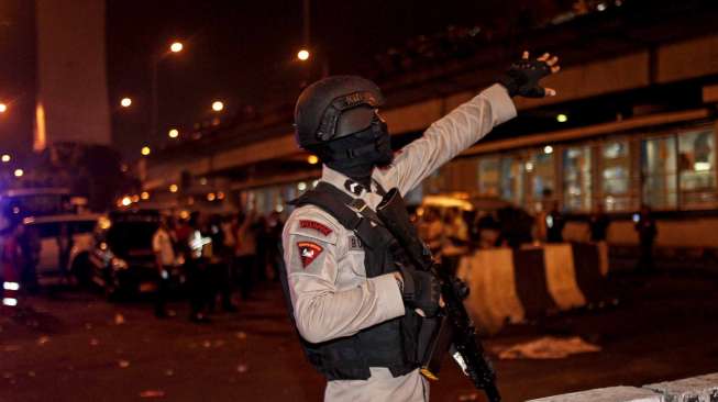 Personil Gegana Brimob Polda Metro Jaya melakukan penyisiran di lokasi ledakan yang diduga bom di Terminal Kampung Melayu, Jakarta Timur, Rabu (24/5) malam. Sementara anggota polisi lainnya mengamankan sekitar lokasi [Suara.com/Kurniawan Mas'ud]