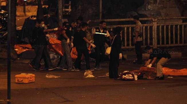 Personil Inafis dan Labfor Polri mengevakuasi jenazah dan potongan tubuh korban ledakan di Terminal Kampung Melayu, Jaktim, (25/5) dini hari. Potongan tubuh dan satu jasad di atas motor dievakuasi untuk diidentifikasi. [Suara.com/Kurniawan Mas'ud]