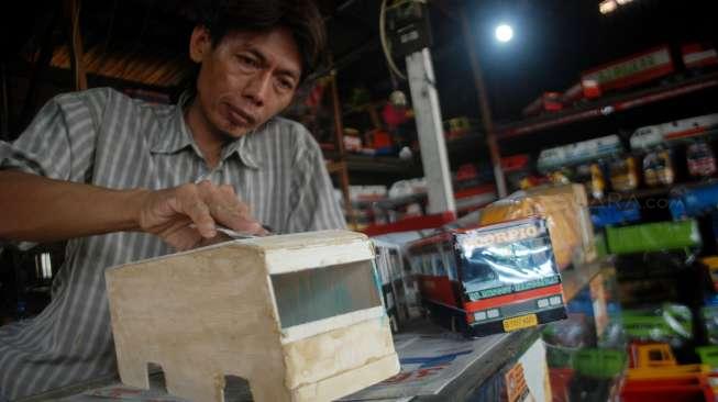 Pelaku Industri Kecil dan Menengah (IKM) menata dagangan berupa replika truk berbahan kayu di Jakarta, Rabu (21/6). [Suara.com/Oke Atmaja]