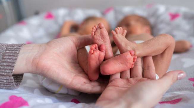 Seorang pegang kaki bayi kembarnya yang lahir prematur. [shutterstock]