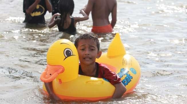 Pengunjung bermain di Pantai Ancol, Jakarta, Rabu (28/6). (Suara.com/Oke Atmaja)