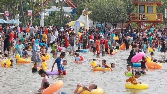 Pengunjung bermain di Pantai Ancol, Jakarta, Rabu (28/6). (Suara.com/Oke Atmaja)