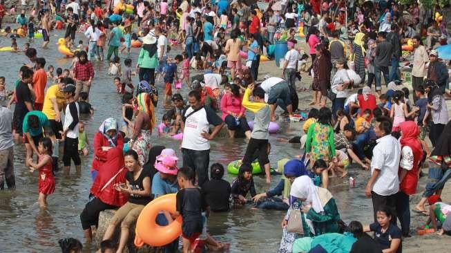 Pengunjung bermain di Pantai Ancol, Jakarta, Rabu (28/6). (Suara.com/Oke Atmaja)