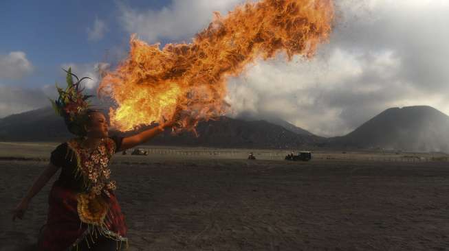 Seorang penari menyemburkan api saat menarikan Tari Pepe' Bainea asal Gowa, Sulawesi Selatan, pada pertunjukan Eksotika Bromo di Lautan Pasir kawasan Taman Nasional Bromo Tengger Semeru, Probolinggo, Jawa Timur, Sabtu (8/7/2017). [Antara/Zabur Karuru]