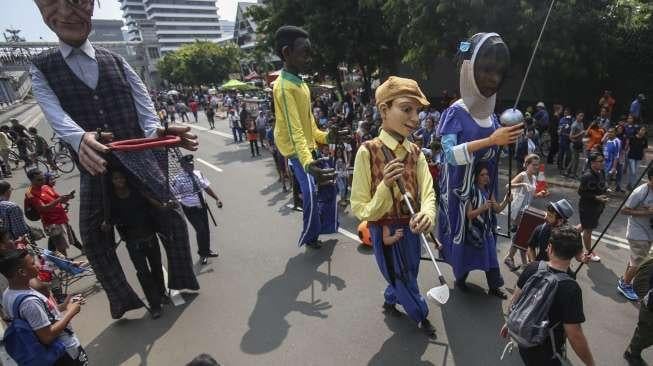 Empat boneka asal Prancis dari Kelompok teater Les Grandes Personnes hibur warga saat berlangsungnya Car Free Day (CFD) di Jakarta, Minggu (9/7). [Suara.com/Kurniawan Mas'ud]