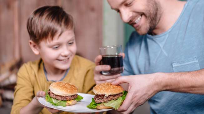Ilustrasi ayah dan anak lelakinya sedang asyik menyantap burger dan minuman bersoda. (Shutterstock)