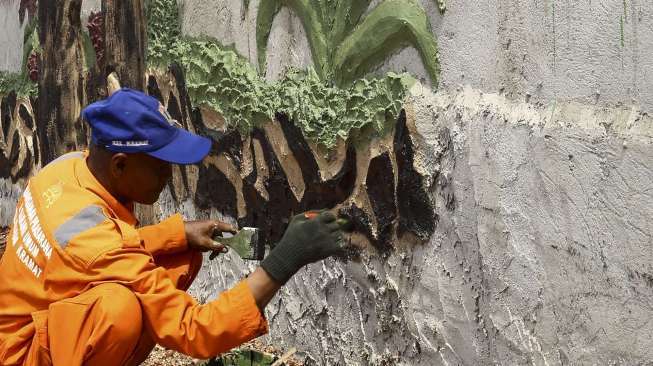 Petugas penanganan prasana dan sarana umum mengecat dinding taman bekas lokasi bangunan liar di kawasan Kramat, Senen, Jakarta, Senin (17/7).