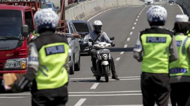 Petugas kepolisian melakukan penindakan kepada pengendara sepeda motor yang melanggar larangan melintas di jalan layang non tol Casablanca, Jakarta Selatan, Rabu (26/7/2017). [Suara.com/Kurniawan Mas'ud]