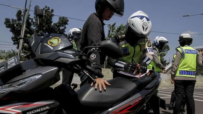 Polisi tampak melakukan penindakan kepada pengendara sepeda motor yang melanggar larangan melintas di jalan layang non tol Casablanca, Jakarta Selatan, Rabu (26/7/2017). [Suara.com/Kurniawan Mas'ud]