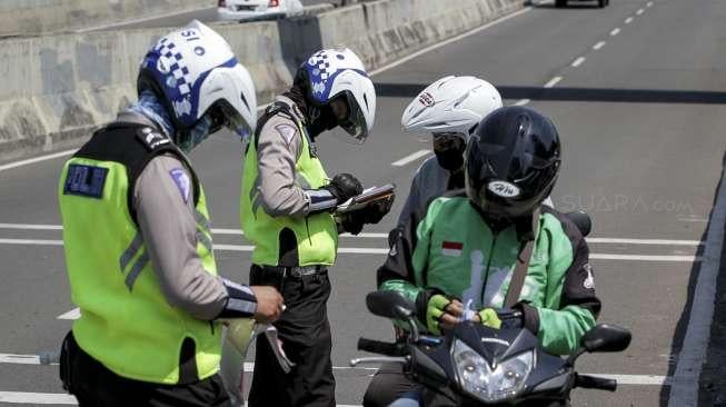 Petugas polisi melakukan penindakan kepada pengendara sepeda motor yang melanggar larangan melintas di jalan layang non tol Casablanca, Jakarta Selatan, Rabu (26/7/2017). [Suara.com/Kurniawan Mas'ud]