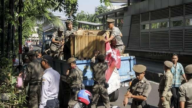 Petugas Satpol PP melakukan penertiban pedagang kaki lima yang berjualan di trotoar jalan kawasan Jatinegara, Jakarta, Rabu (2/8).