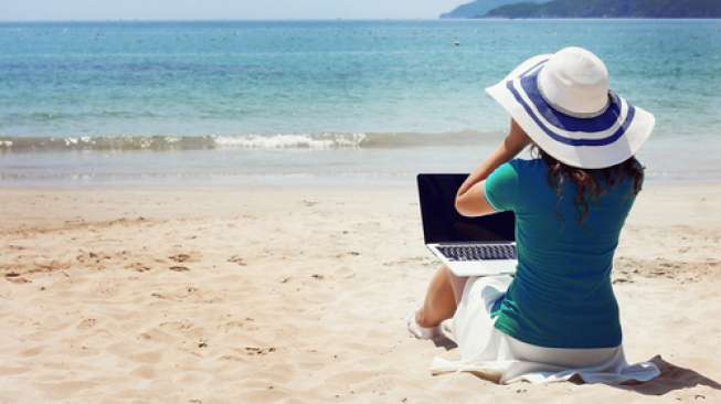 Ilustrasi perempuan menyelesaikan tugas kantor sambil menikmati liburan. (Shutterstock)