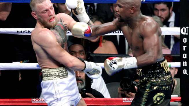 Floyd Mayweather Jr (kanan) mendaratkan hook kanan ke wajah Conor McGregor dalam duel yang dimenanginya lewat TKO ronde ke-10 di T-Mobile Arena, Nevada, Amerika Serikat, Sabtu (26/8/2017). [AFP/John Gurzinski]