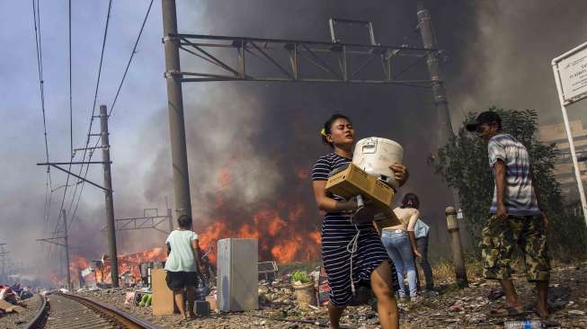 Warga berusaha menyelamatkan harta bendanya dari lokasi kebakaran di Kampung Bandan, Jakarta, Sabtu (16/9).