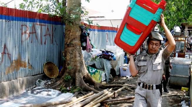 Petugas Satpol PP tampak menggotong kursi saat melakukan penertiban pedagang kaki lima (PKL) di sepanjang trotoar kawasan Stasiun Manggarai, Jakarta, Senin (18/9/2017). [Suara.com/Oke Atmaja]